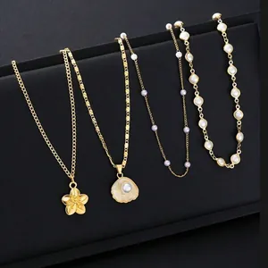 Golden brass necklaces with flower shell and pearl pendants on dark textured background
