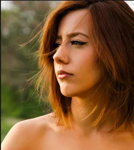 Close-up of minimalist gold nose ring on female model with soft natural background