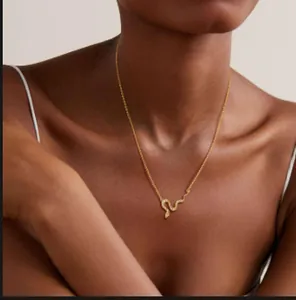Gros plan du collier serpent doré orné de cristaux scintillants sur le décolleté