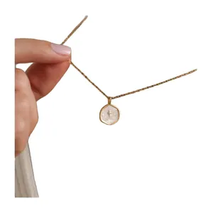 14K gold plated stainless steel hexagonal cross pendant necklace held by hand
