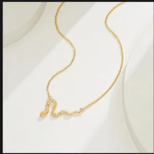Collier serpent doré avec cristaux micro-pave sur un support d'exposition blanc