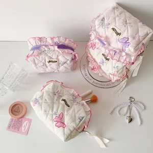 Detailed macro view of quilted butterfly print makeup bags with delicate pink ruffle edges