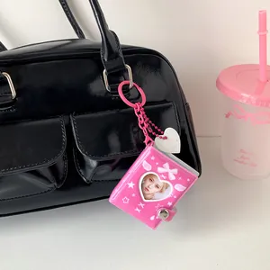 Mini 2-inch pink heart-shaped keychain photo album hanging on a black leather handbag