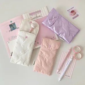 Three padded bow pencil cases in white, pink, and purple with heart button closure