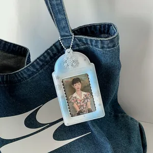 Détail d'un porte-carte en acrylique bleu à flocons accroché à un sac en jean