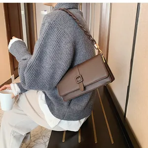 Détail du sac bandoulière en cuir marron foncé avec bandoulière tressée et boucle