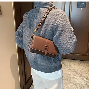 Gros plan sur un sac bandoulière vintage marron avec une bandoulière tressée unique