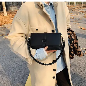 Détail du sac bandoulière en cuir noir avec sangle tissée et finitions dorées