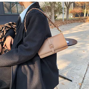 Gros plan sur un sac bandoulière vintage en cuir marron avec bandoulière tissée mate