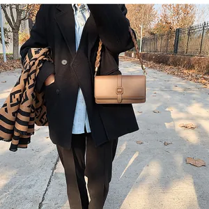 Détail du sac bandoulière marron avec bandoulière tressée et boucle carrée élégante