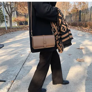 Détail d'un sac bandoulière carré en cuir marron dans une scène de mode urbaine d'automne