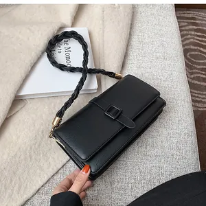 Détail d'un sac à bandoulière en cuir noir avec sangle tressée et boucles dorées