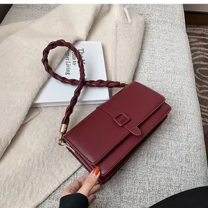 Détail du sac à bandoulière bordeaux avec bandoulière tressée et boucle carrée élégante