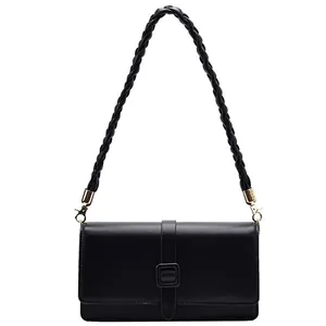 Sac bandoulière en cuir noir avec poignée tressée et détails dorés sur fond blanc