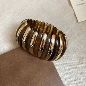 Detail of wide stretch bracelet with gold metal and amber resin bars on leather