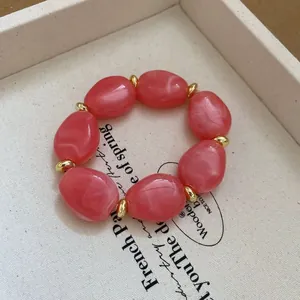 Detailed shot of pink marble acrylic beads and gold ring spacers on a beaded bracelet