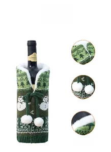 Detail showing green knitted Christmas wine bottle cover with snowman pattern and pom-poms