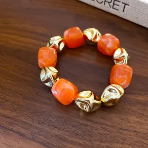 Detail view of retro acrylic resin beads and golden metallic beads on wood surface