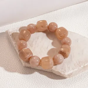 Close-up of light brown marbled acrylic beads showing round and cubic textures