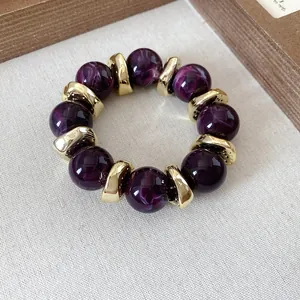 Detail of beaded bracelet with purple marble resin beads and gold irregular metal accents