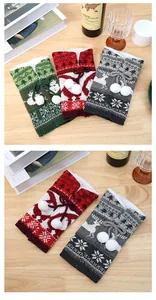 Close-up of thick knitted Christmas wine bottle covers with reindeer and snowflake patterns
