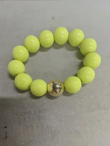 Detail of yellow acrylic beaded bracelet with a central golden metallic bead accent