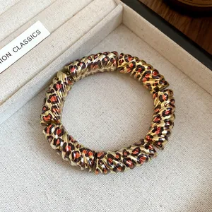 Detailed close-up of golden spiral bracelet with leopard print pattern in jewelry box