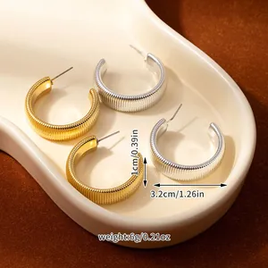 Detail view of gold and silver C-shaped textured earrings with 3.2cm size and 6g weight