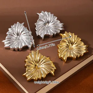 Detailed view of layered floral earrings in gold and silver finish with metal texture