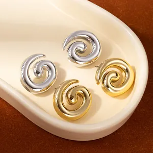 Minimalist spiral hoop earrings in polished gold and silver finishes on a tray