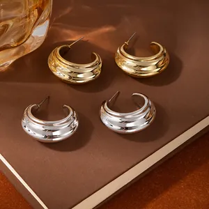 Macro view of chunky C-shape textured hoop earrings in gold and silver finish