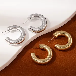 Macro shot of gold and silver thick hoop earrings with textured horizontal ribbed details