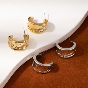 Detail of gold and silver C-shaped earrings with unique hammered texture and metallic finish