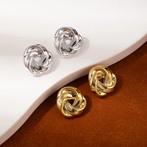 Detailed macro view of the twisted knot stud earrings in polished gold and silver finishes