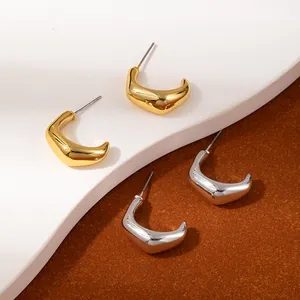 Detail of minimalist moon-shaped gold and silver earrings on a geometric display