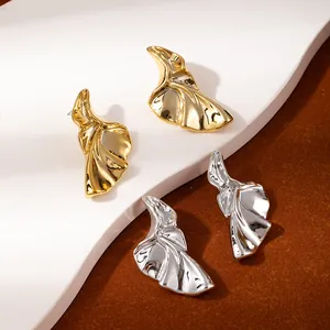 Detail of artistic metallic flower earrings in polished gold and silver finishes