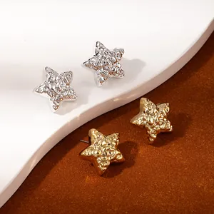Macro detail of star-shaped earrings set in gold and silver with textured finish