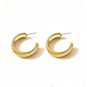 Minimalist gold hoop earrings with textured vertical ridges and polished inner finish