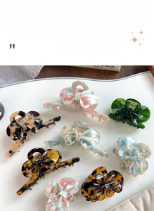 Detailed view of acetate bow hair claws in tortoiseshell and emerald on a white tray
