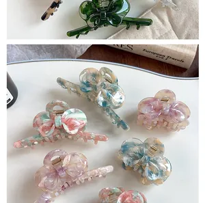 Detailed view of acetate bow hair claws with marble texture and premium metal springs