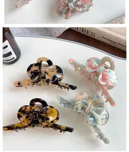 Detailed macro view of four acetate bow hair claws with marble texture and metal spring