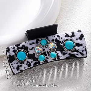Detail of western cow print hair claw clip with turquoise stones and rhinestones