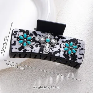 Detailed view of hair claw clip with cow print and turquoise floral cross accents
