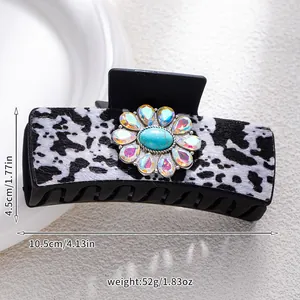 Detailed view of hair claw clip with cow print texture and turquoise floral center