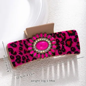 Detail view of large turquoise claw clip with pink leopard velvet and floral decoration