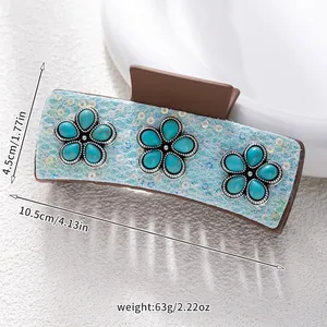 Detail view of ethnic hair claw with turquoise floral inlay and blue sequins, 10.5cm long