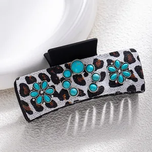 Detail of bohemian hair claw clip with leopard print and turquoise stone embellishments