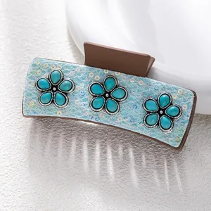 Detail of bohemian hair claw with turquoise flowers and shimmering blue glitter finish