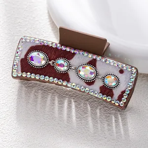 Macro shot of hair claw featuring cow print fabric, colorful rhinestones and faux gems