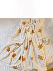 Detail of soft white coral fleece bath towel with yellow bear pattern and elastic top